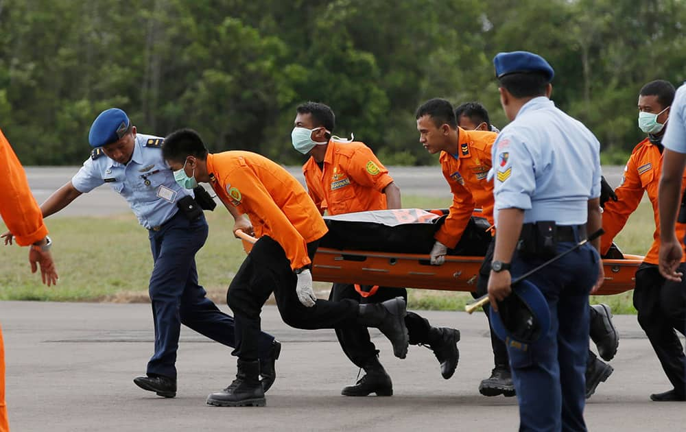 Officers of the National Search And Rescue Agency (BASARNAS) carry a body of one of the victims on board the ill-fated AirAsia Flight 8501, from a helicopter upon arrival at the airport in Pangkalan Bun, Indonesia.