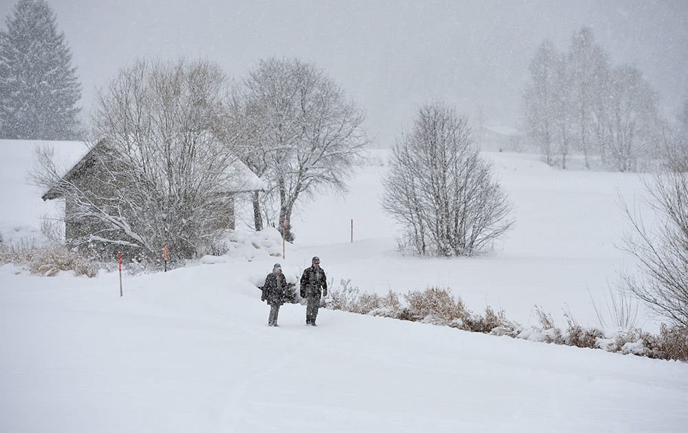 Two strollers walk on a snow covered track in Lofer, Austrian province of Salzburg. Weather forecasts predict snow falls for the next days in this alpine region.