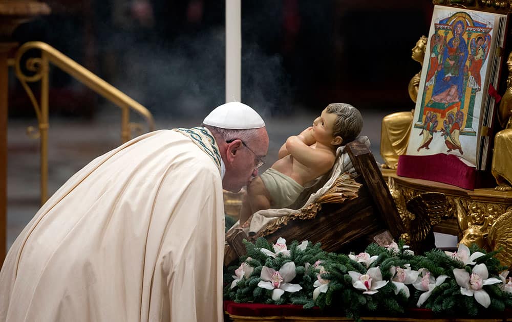 Pope Francis kisses a statue of the baby Jesus as he arrives to celebrate the new year's eve vespers Mass in St. Peter's Basilica at the Vatican.