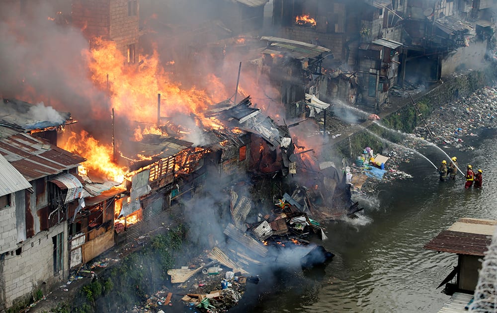 Firefighters fight the fire at shanties from a creek in suburban Quezon city, north of Manila, Philippines during an early morning fire.