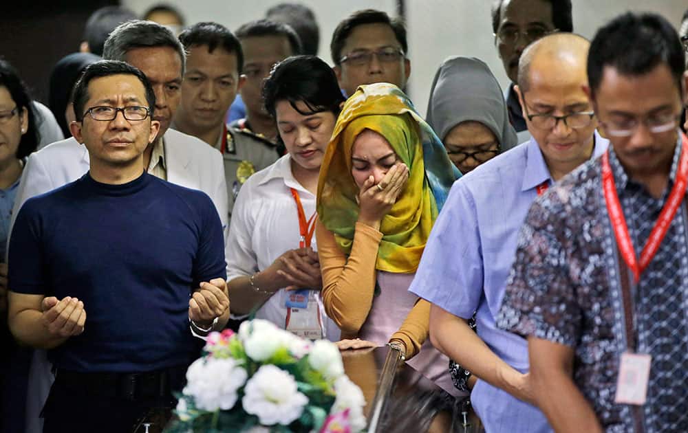 Relatives and airline officials pray during the handover of the body of Hayati Lutfiah, one of the victims of AirAsia Flight 8501, to her family at the police hospital in Surabaya, East Java, Indonesia.