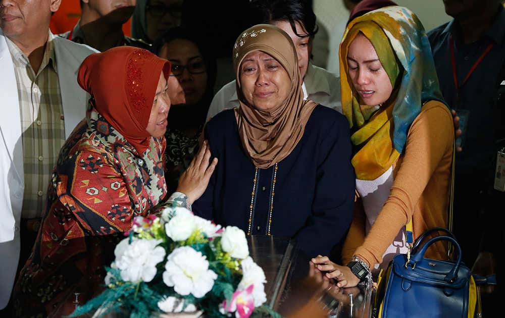 Relatives weep during the handover ceremony of the body of Hayati Lutfiah, one of the victims of AirAsia Flight 8501, to her family at the police hospital in Surabaya, East Java, Indonesia.