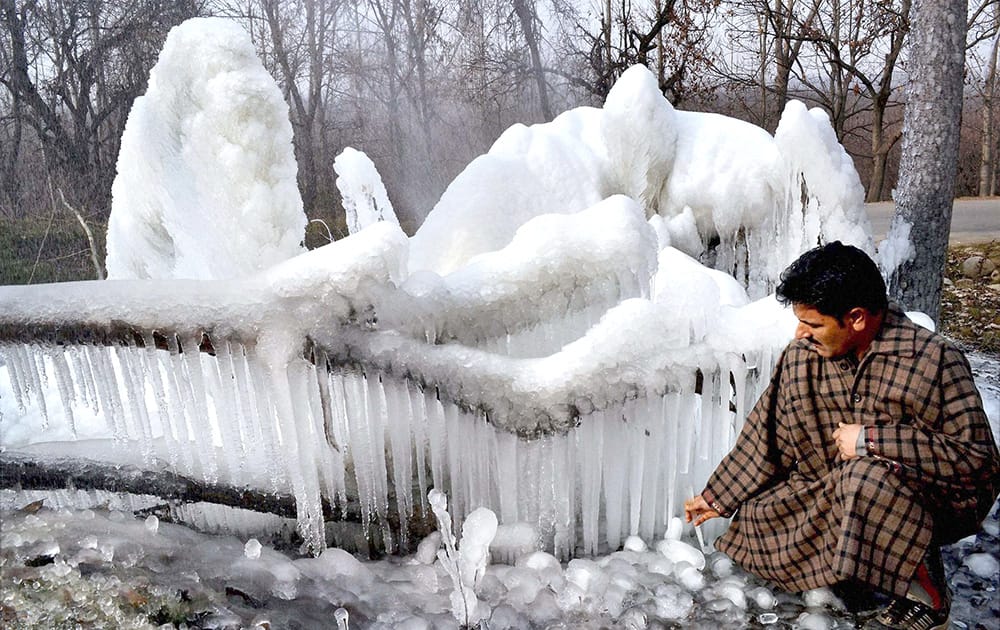 A man breaks icicles formed in a stream and in trees due to sub zero tempatures in the valley, in Srinagar.