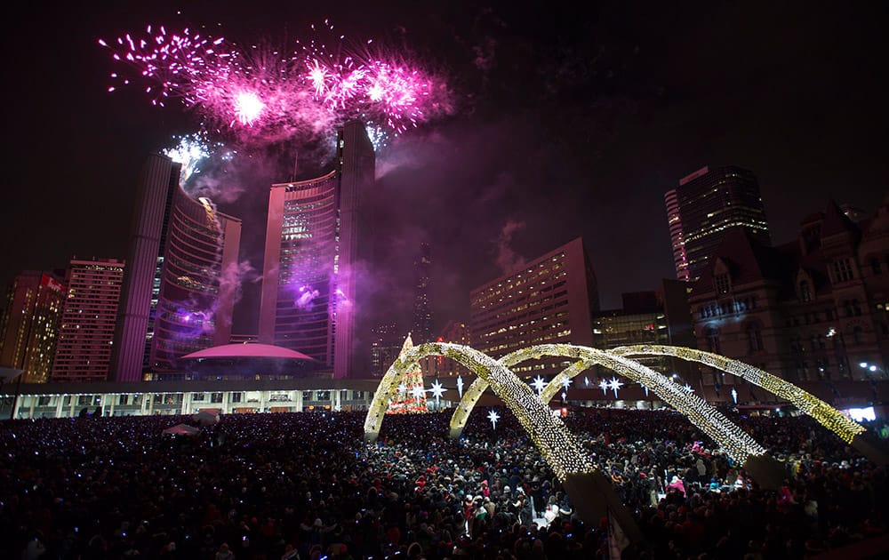 Fireworks explode in front of City Hall as revelers pack Nathan Phillips Square for New Year's celebrations in Toronto.