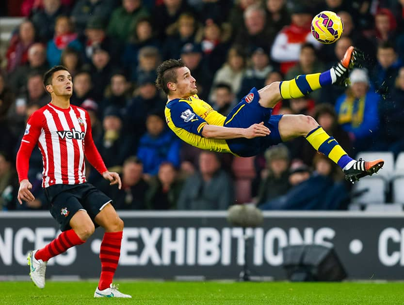 Southamptons Dusan Tadic watches Arsenals Mathieu Debuchy clear an overhead shot during the English Premier League soccer match at St Marys Stadium, Southampton, England.