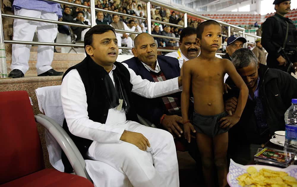 A young wrestler poses for photographes with Uttar Pradesh Chief Minister Akhilesh Yadav, after wining a local wrestling championship during Saifai festival, in Saifai village, Uttar Pradesh.