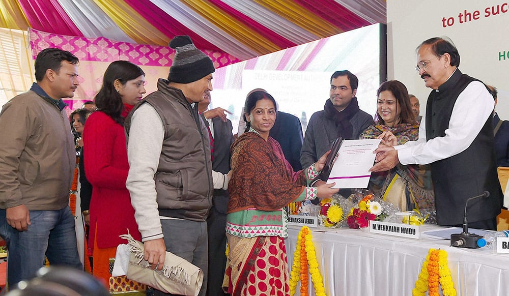 Union Minister for Urban Development Venkaiah Naidu with MP Meenakshi Lekhi handing over allotment cum possession letters to the successful allottees of DDA housing scheme 2014, in New Delhi.