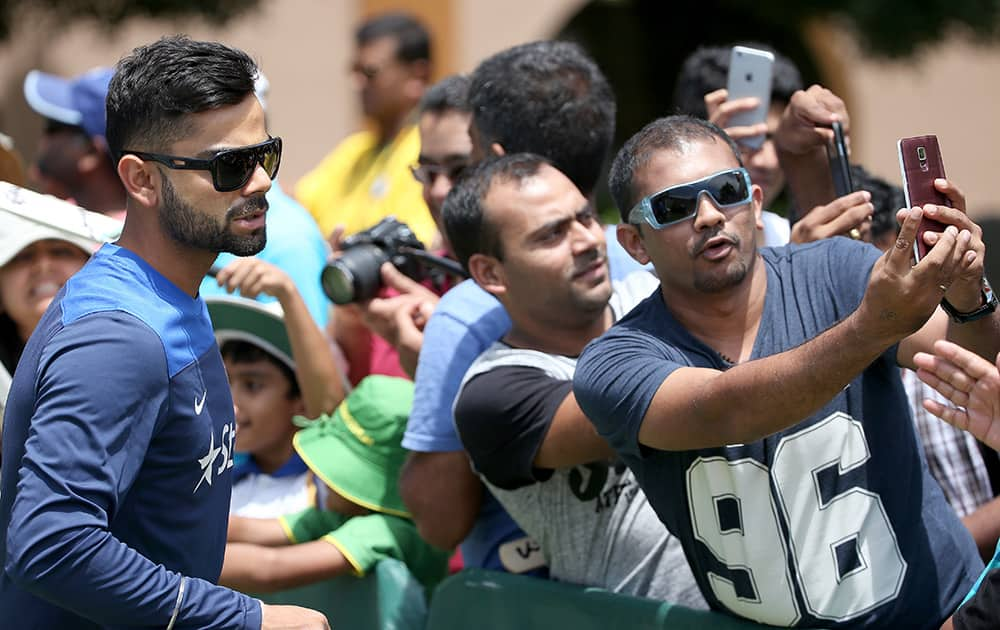 India's cricket captain Virat Kohli, left, poses for photos for fans as his team arrives at training before their cricket test match against Australia in Sydney, Sunday.