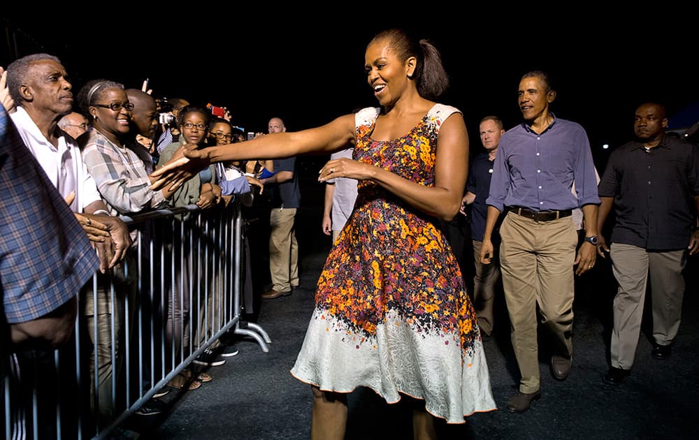 First lady Michelle Obama and President Barack Obama greet people on the tarmac before boarding Air Force One, at Joint Base Pearl Harbor-Hickam in Honolulu, Hawaii, to return to Washington with their family after their annual family vacation.