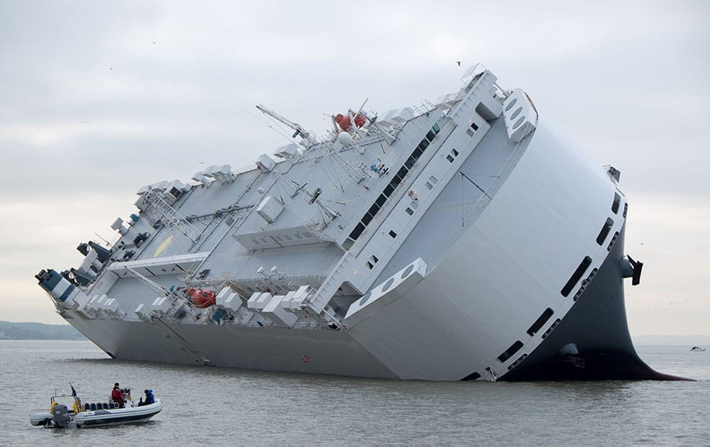 A small boat sails past the Hoegh Osaka car transporter cargo ship that ran aground in the Solent, off the Isle of Wight.