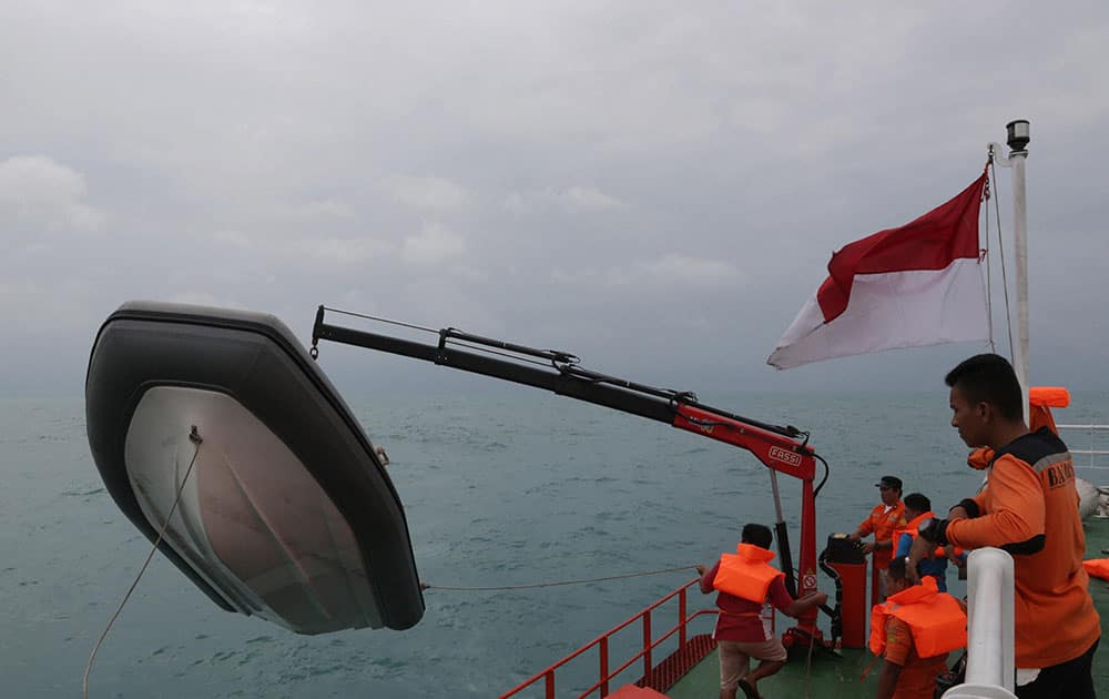 Members of the National Search And Rescue Agency (BASARNAS) unload a rubber boat from their ship during a search operation for the victims of AirAsia flight QZ 8501at Java Sea, Indonesia.