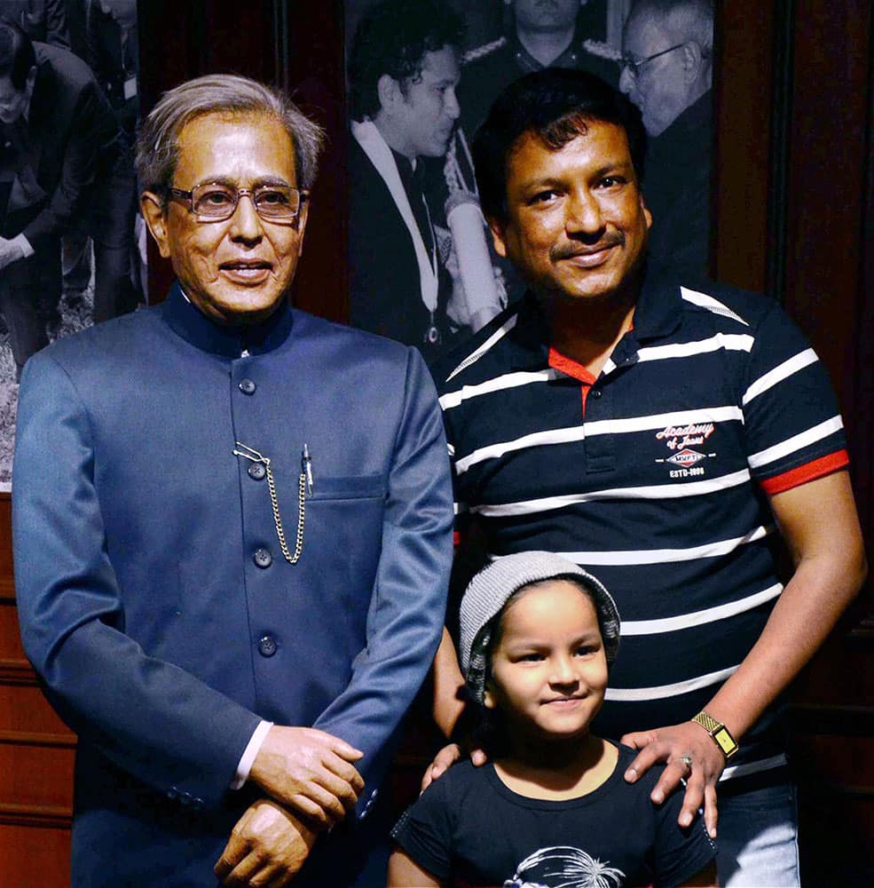 People pose for photographs next to a wax statue of President Pranab Mukherjee at Mothers Wax Museum.