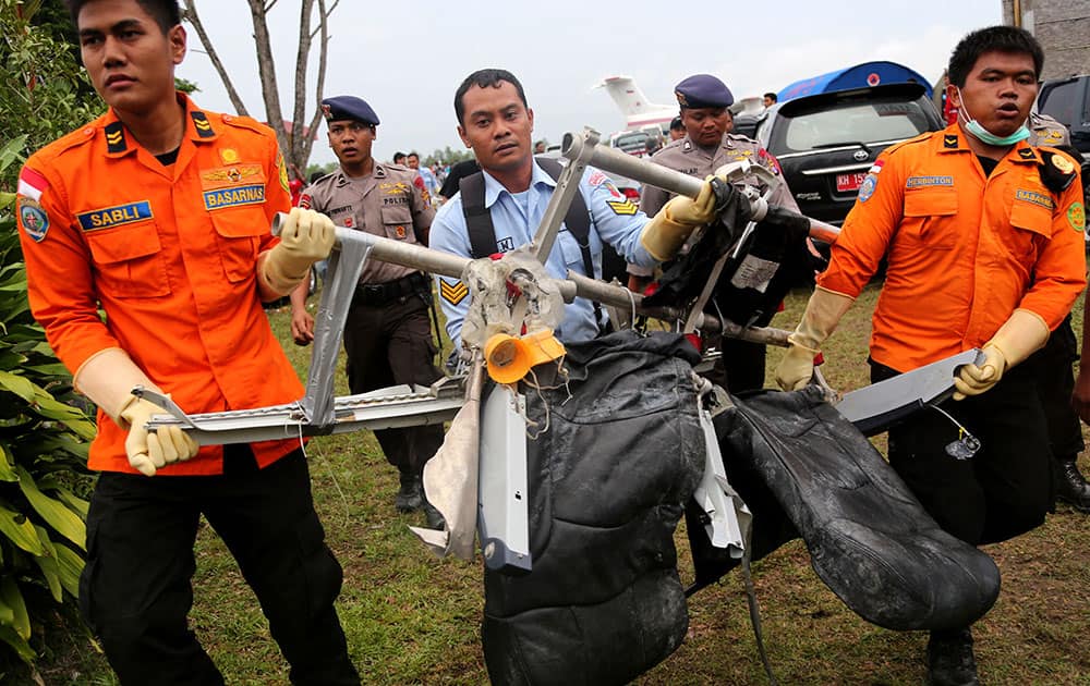 National Search and Rescue Agency personnel carry the seats of AirAsia Flight 8501 after being airlifted by a U.S. Navy helicopter, at the airport in Pangkalan Bun, Indonesia.