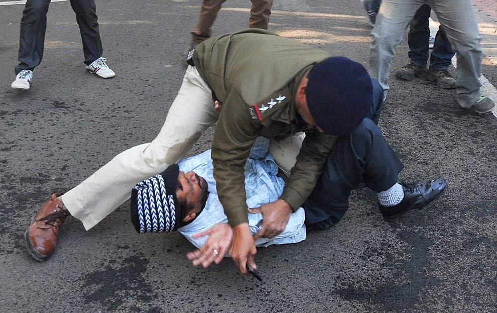 A police officer holds down a man after he tried to commit suicide by self immolation outside Madhya Pradesh Home Minister Babu Lal Gaurs residence in Bhopal.