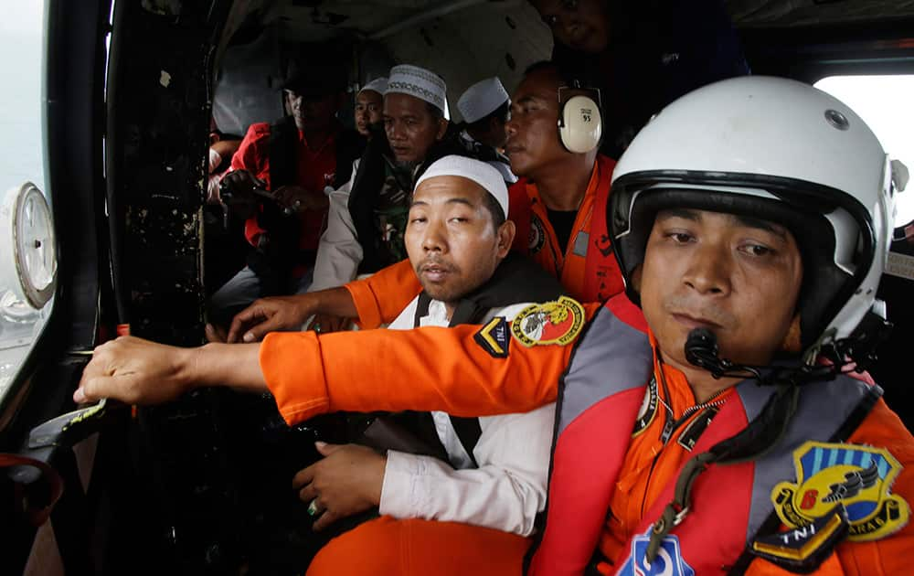 Muslim clerics sit inside an Indonesian Air Force NAS 332 Super Puma helicopter during a flight over the Java Sea off Pangkalan Bun, Central Borneo, Indonesia where the ill-fated jetliner went down to offer prayers for the victims.