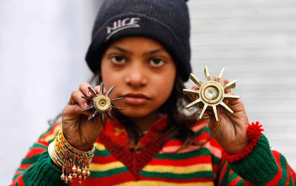 A girl displays a mortar shell allegedly fired from the Pakistan side of the border at Bainglad village in Samba sector, about 52 kilometers (32 miles) from Jammu, India.