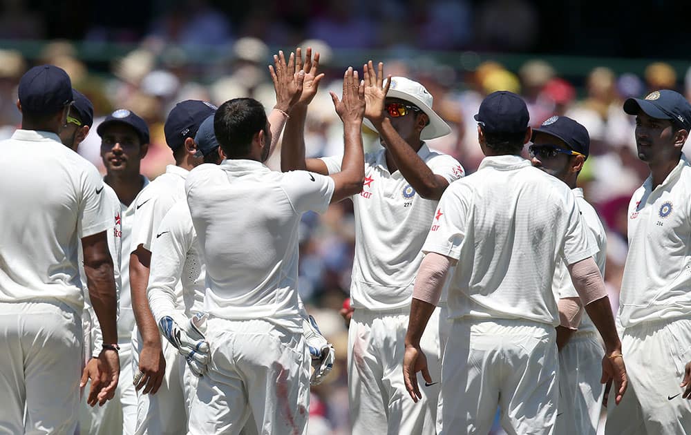 India's Mohammad Shami, center left, and teammate Ravichandran Ashwin, center right, celebrate taking the wicket of Australia's Shane Watson for 81 runs on the second day of their cricket test match in Sydney.