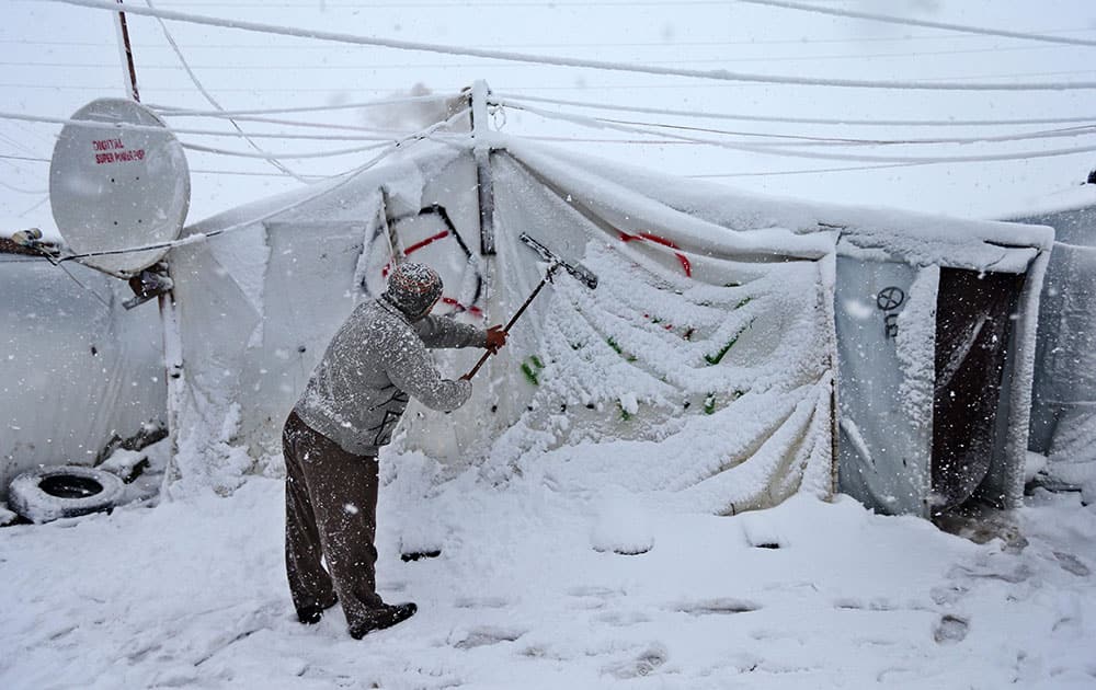 A Syrian man removes the snow from his tent at a refugee camp in Deir Zannoun village, in the Bekaa valley, east Lebanon.