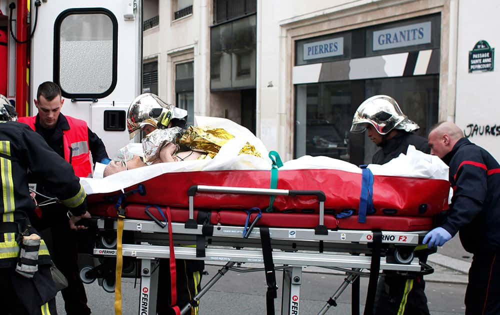 An injured person is transported to an ambulance after a shooting, at the French satirical newspaper Charlie Hebdo's office, in Paris.