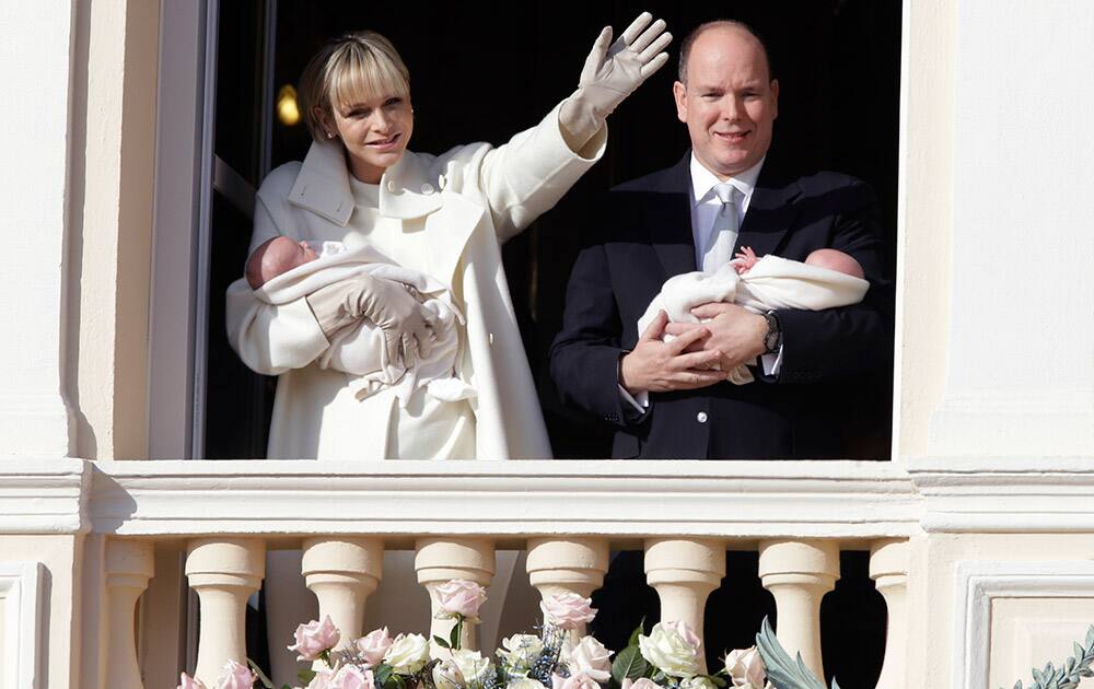 Princess Charlene and Prince Albert appear on a palace balcony, each holding a newborn baby swaddled in white in Monaco. The hereditary heir Prince Jacques and his older sister — by 2 minutes — Gabriella were greeted by a small sea of red-and-white flags and banners.