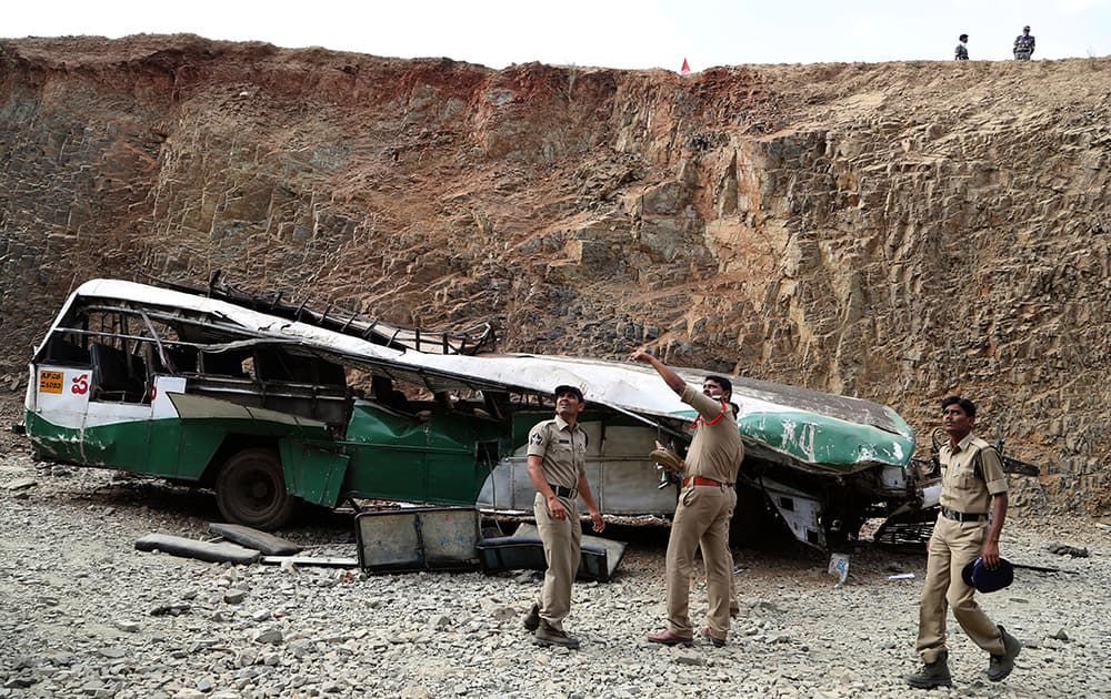 Police officers point at people standing above, as they inspect the wreckage of a bus that fell into a gorge in Penukonda, about 145 kilometers north of Bangalore. The passenger bus veered off a road in southeastern India and fell into the gorge on Wednesday, killing at least 16 people, most of them college and middle school students, police said. More than 50 other people were injured in the accident.