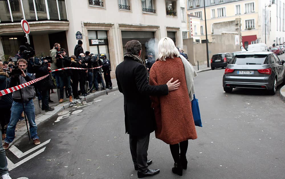 People stand outside the French satirical newspaper Charlie Hebdo's office after a shooting, in Paris.