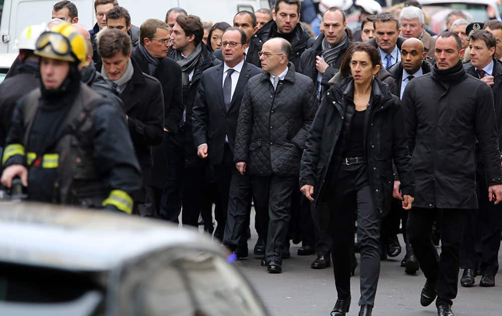 French President Francois Hollande, flanked with French Interior Minister Bernard cazeneuve, walk outside the French satirical newspaper Charlie Hebdo's office, in Paris.
