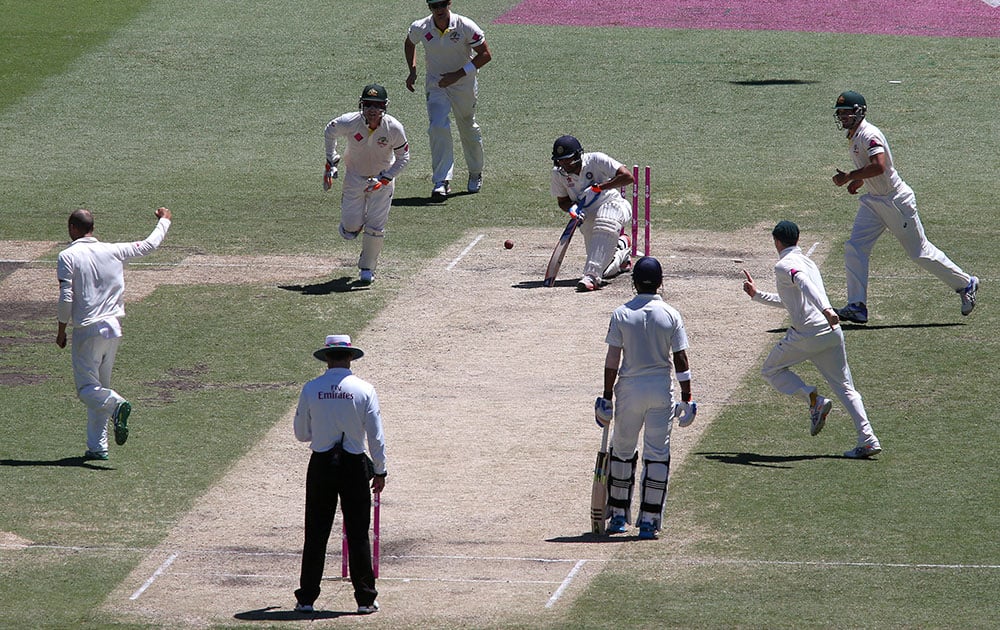 Teammates come running toward Australia's Nathan Lyon, after he bowled out India's Rohit Sharma, for 53 runs on the third day of their cricket test match in Sydney.