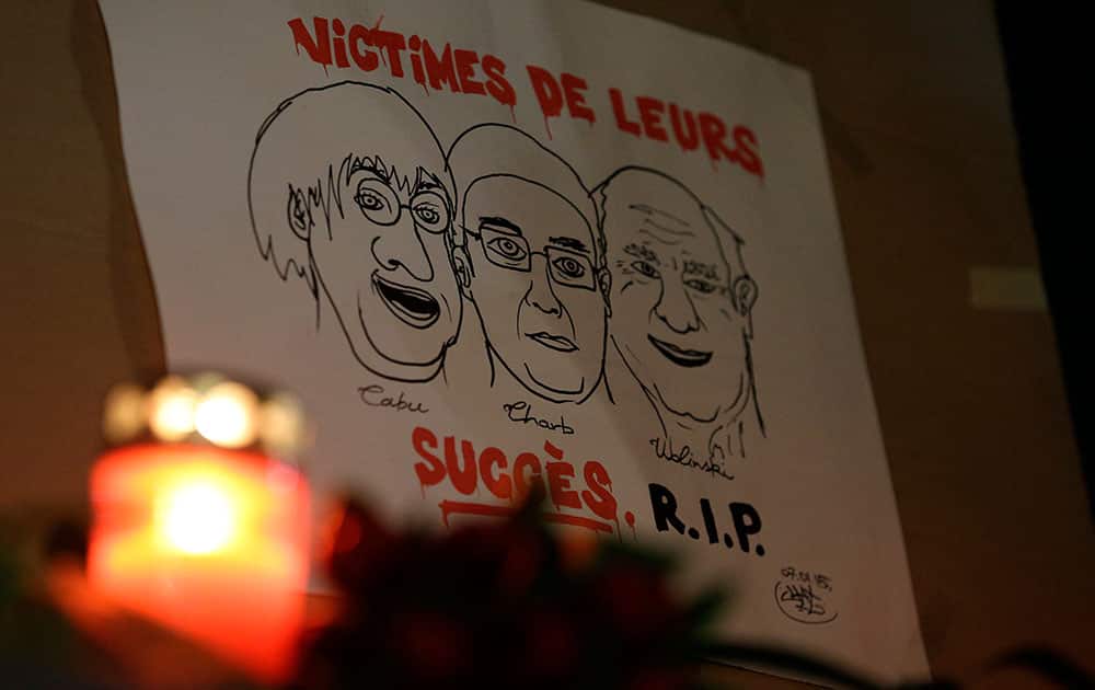 A drawing depicting cartoonist Jean Cabut, Charlie Hebdo editor Stephane Charbonnier and cartoonist Georges Wolinski, all three of whom were killed when masked gunmen stormed the Paris offices of a weekly newspaper Charlie Hebdo and reading in French, 'Victims of their success, R.I.P', is placed outside the French Embassy as people gather to express solidarity with victims of the attack in Berlin, Germany.