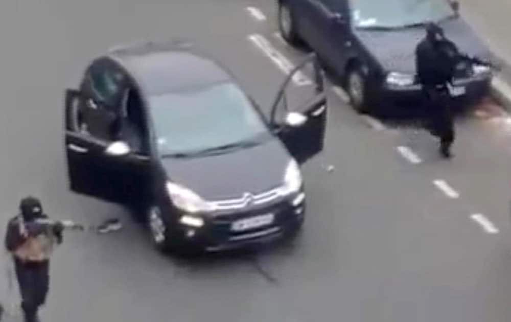 Masked gunman fire their weapons outside the French satirical newspaper Charlie Hebdo's office, in Paris.