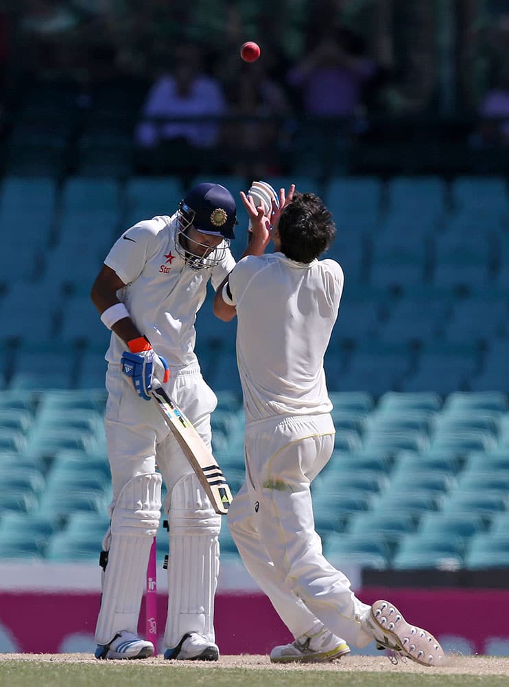 India's Lokesh Rahul, left, covers his head as Australia's Mitchell Starc races in to catch him out for 110 on the third day of their cricket test match in Sydney.