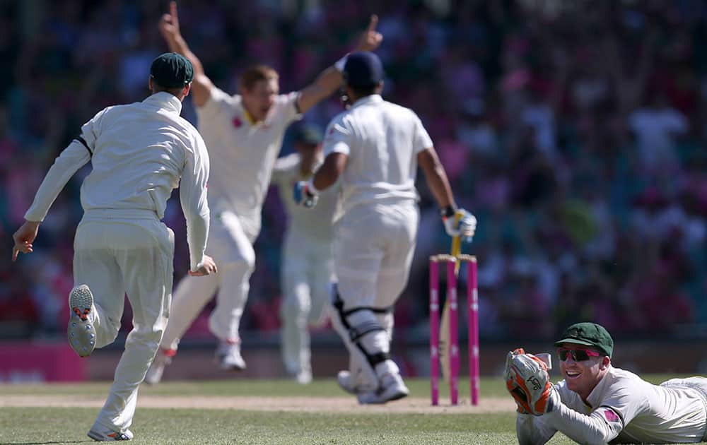 Australia's Brad Haddin, right, lies on the ground smiling after catching out India's Suresh Raina for no score off the bowling of Shane Watson, second from left, on the third day of their cricket test match in Sydney.