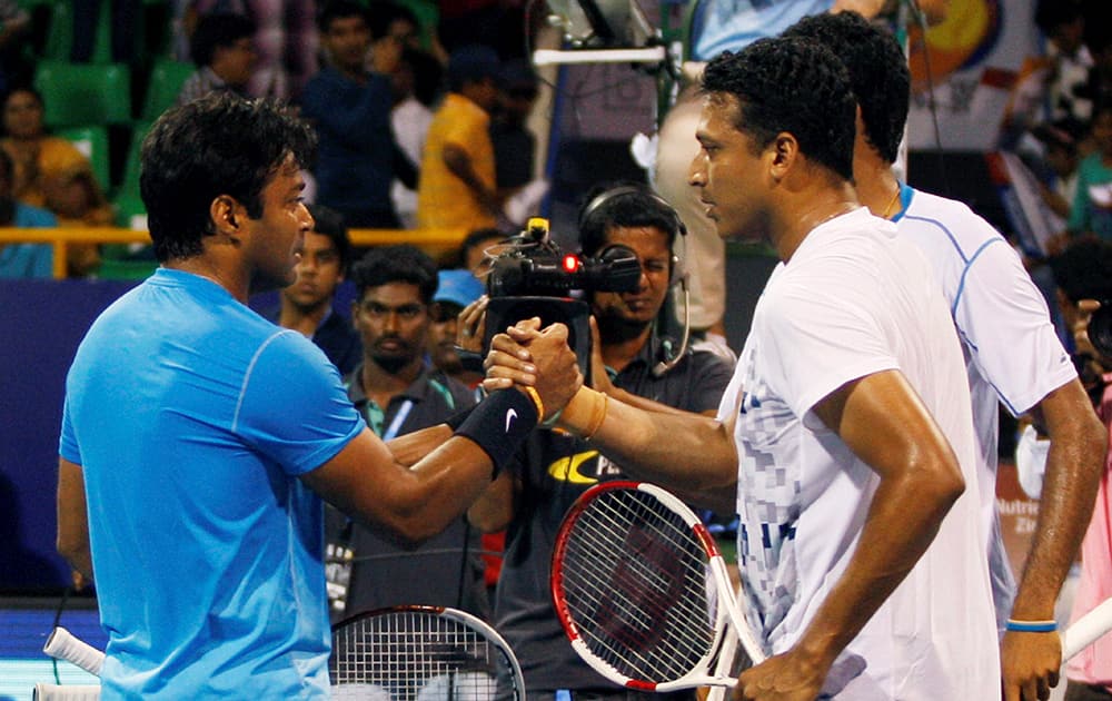 Tennis player Leander Paes and South African tennis player Raven Klaasen shake hands with Indias Mahesh Bhupathi and Saketh Myneni after winning their match at ATP Chennai Open 2015 at SDAT Tennis Stadium in Chennai.