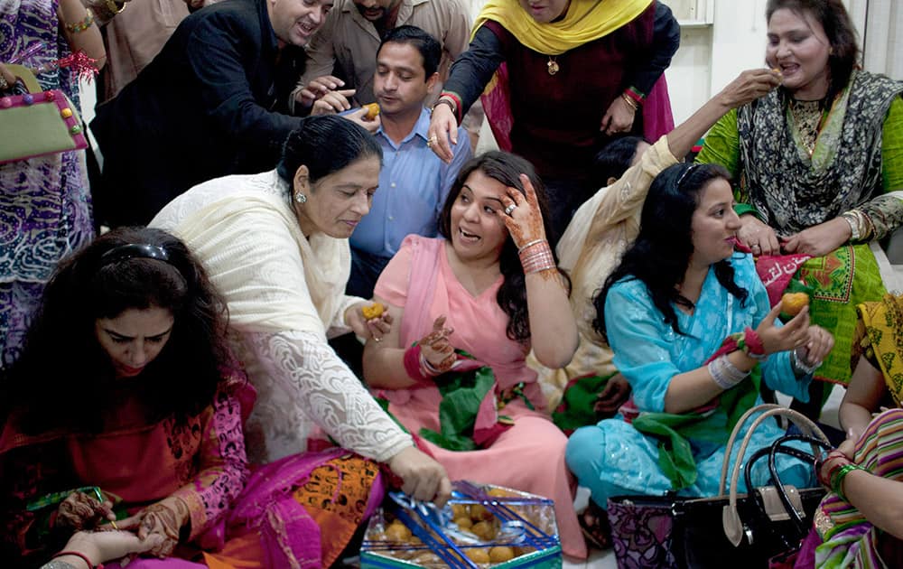Supporters of Pakistan's cricketer-turned-politician Imran Khan exchange sweets, as they celebrate the marriage of their leader in Karachi, Pakistan.