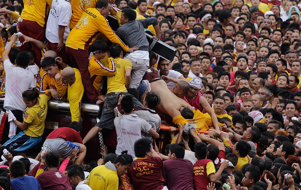 An unconscious devotee is loaded into a stretcher during a raucous procession to celebrate the feast day of the Black Nazarene in Manila, Philippines.