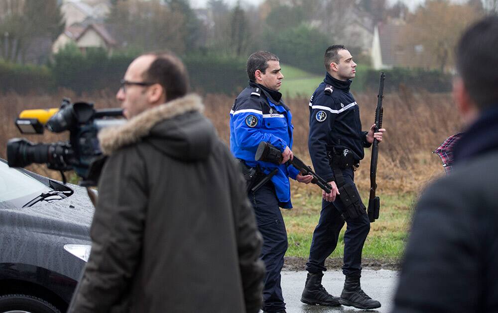 Gendarmes holding firearms walk past reporters in Dammartin-en-Goele, northeast of Paris. Brothers suspected in a newspaper terror attack were cornered with a hostage inside a printing house on Friday, after they hijacked a car and police followed them to a village near Paris' main airport.