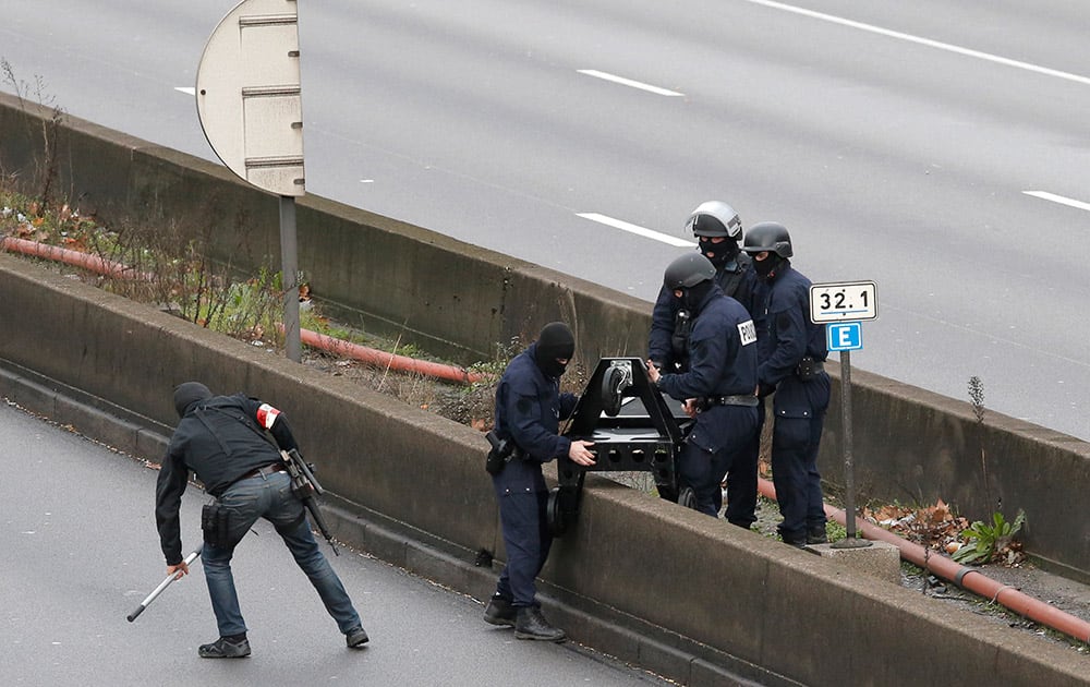 Hooded police officers cross the closed ring road that circles Paris near a hostage-taking situation at a kosher market in Paris.