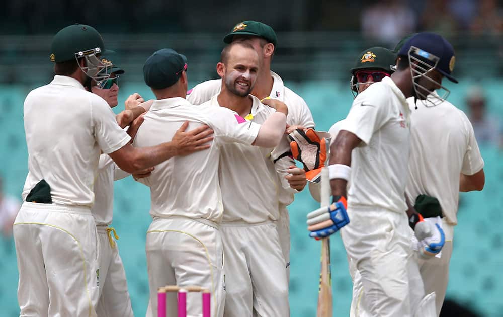 Australia's Nathan Lyon, celebrates with teammates after he dismissed India's Lokesh Rahul, right, for 16 runs on the fifth day of their cricket test match in Sydney.