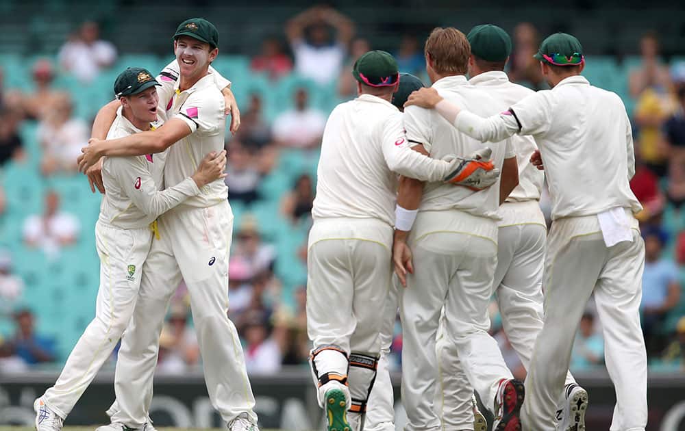 Australia's Steve Smith, celebrates with Josh Hazelwood after catching out India's Rohit Sharma for 39 runs on the fifth day of their cricket test match in Sydney.