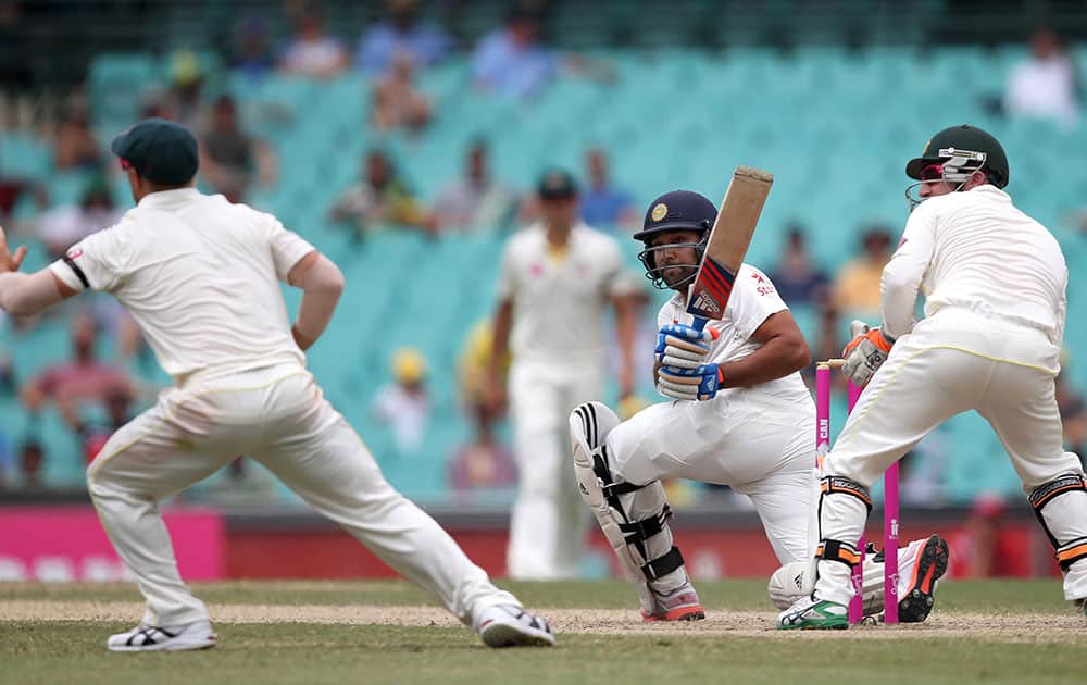 Rohit Sharma sweeps past Australia's Brad Haddin and David Warner, left, on the fifth day of their cricket test match in Sydney.