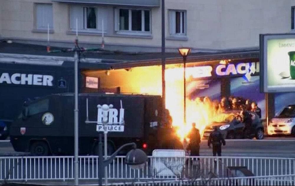 This image taken from a video provided by PFMTV, police officers storm a kosher grocery to end a hostage situation in Paris.