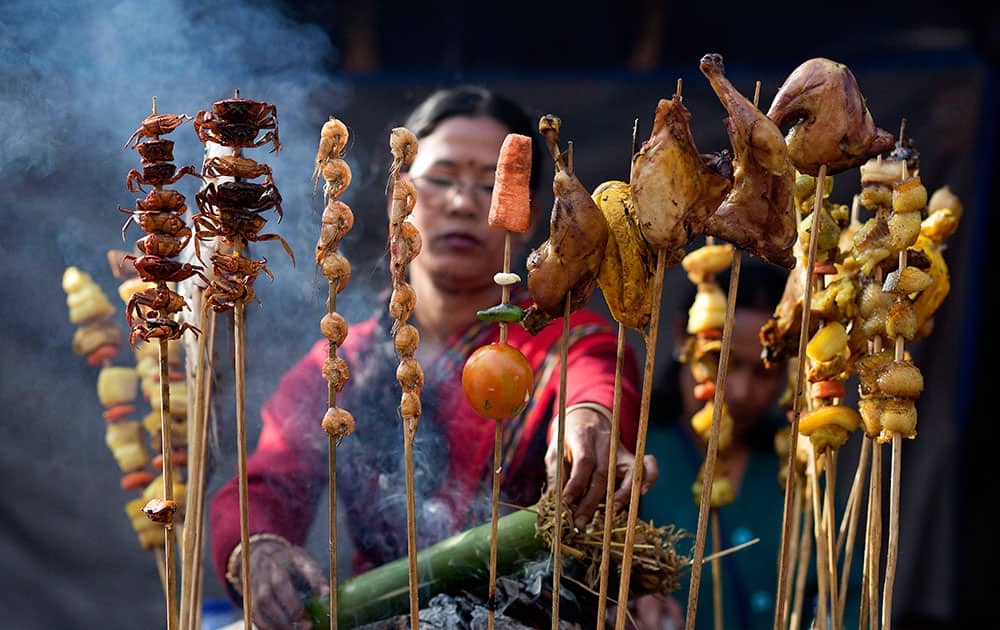 A Mishing tribal woman smokes meat at a temporary stall during an ongoing ethnic food festival as part of festivities to mark Bhogali Bihu festival in Gauhati, India.