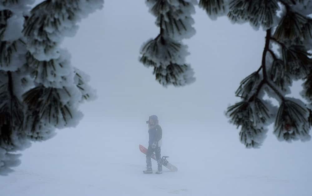 A man with his snowboard walks on the snow after a heavy snowfall on Troodos mountain, Cyprus.