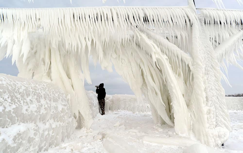 Ice coats the railings leading to the North Pier Lighthouses as a photographers takes pictures in St. Joseph, Mich.