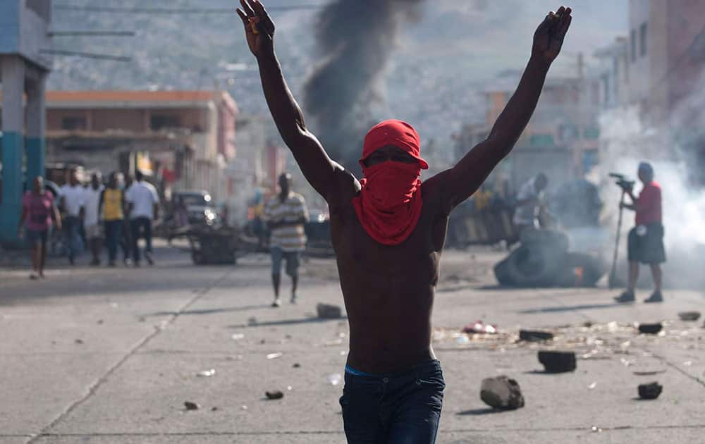 A masked protester gestures during a protest demanding the resignation of President Michel Martelly in Port-au-Prince, Haiti.