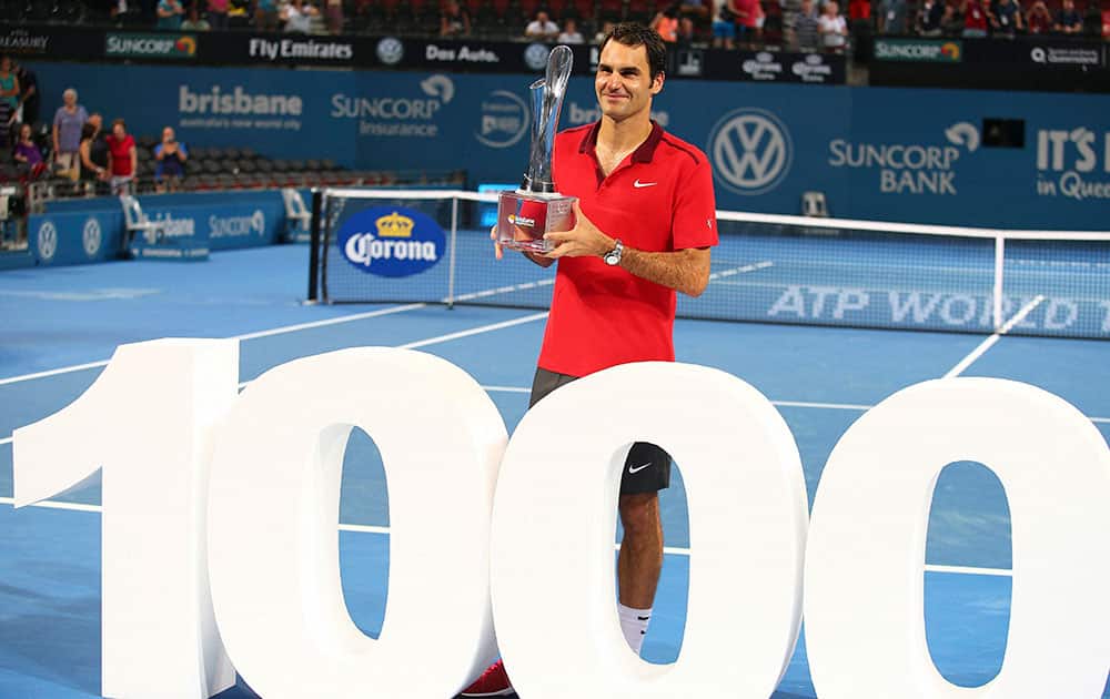 Roger Federer of Switzerland holds the winners trophy and pose for photos after he won his 1000th career title in the mens final match against Milos Raonic of Canada during the Brisbane International tennis tournament.