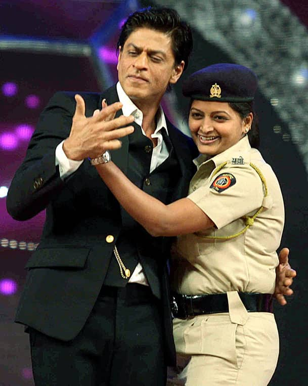 Bollywood actor Shah Rukh Khan with a police woman performs during the Umang Mumbai Police Show 2015 in Mumbai.