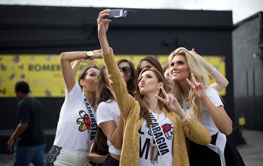 Miss Nicaragua, Marline Barberena, front, takes a selfie with other contestants after they painted on a wall in Miami's Wynwood area.