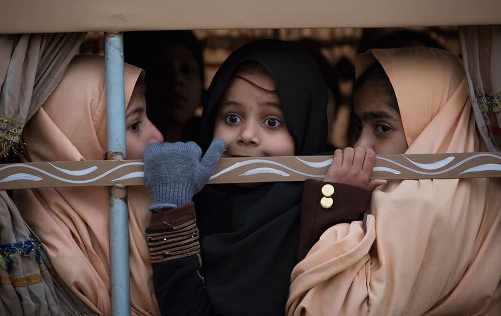 Pakistani students look out from a vehicle on their way to school near the Army Public School which was targeted by Taliban militants last year, in Peshawar, Pakistan.