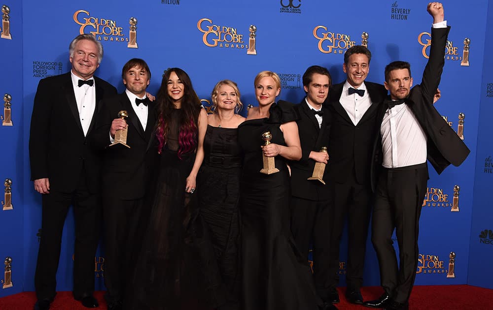 Jonathan Sehring, from left, Richard Linklater, Lorelei Linklater, Cathleen Sutherland, Patricia Arquette, Ellar Coltrane, John Sloss, and Ethan Hawke pose in the press room with the award for best motion picture - drama for “Boyhood” at the 72nd annual Golden Globe Awards.